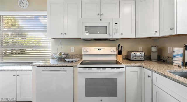 kitchen featuring white appliances, a toaster, white cabinetry, and light stone counters