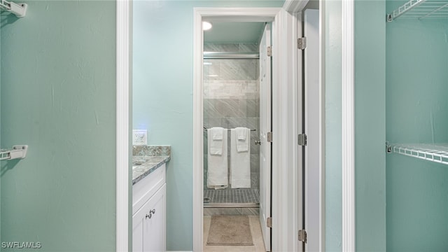 full bath featuring a spacious closet, a stall shower, vanity, and tile patterned floors