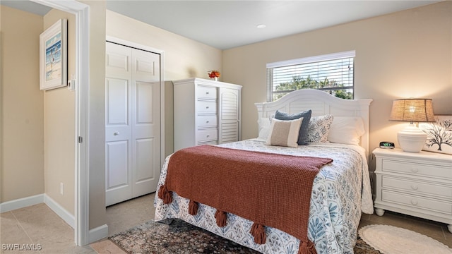 bedroom with light tile patterned floors, a closet, and baseboards