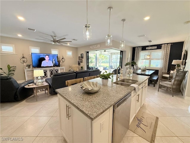 kitchen with light stone counters, a sink, visible vents, open floor plan, and stainless steel dishwasher