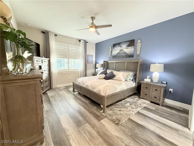 bedroom with ceiling fan, wood finished floors, and baseboards