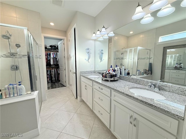 full bath with a spacious closet, a stall shower, a sink, and visible vents