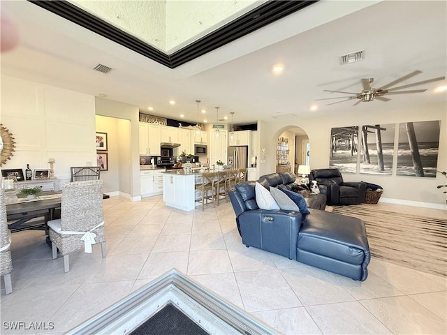 living area with light tile patterned floors, visible vents, and arched walkways