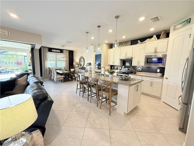 kitchen with light tile patterned floors, a kitchen bar, stainless steel appliances, and open floor plan