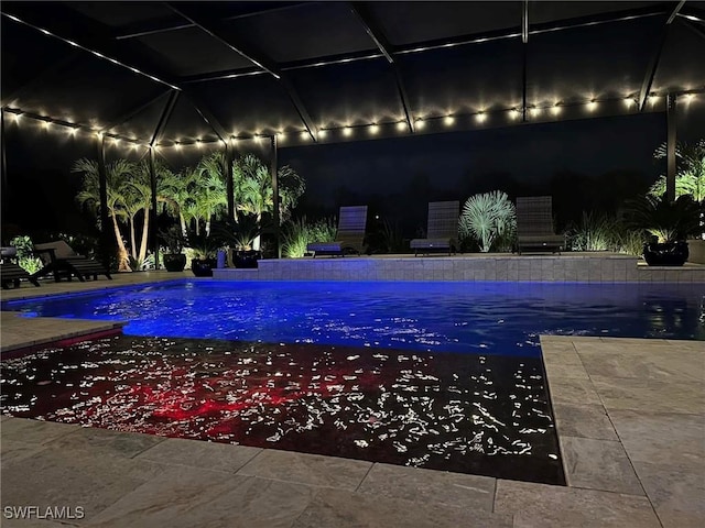 pool at twilight featuring glass enclosure, a patio, and an outdoor pool