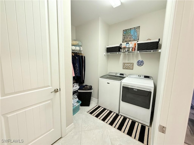 laundry room featuring laundry area, tile patterned flooring, baseboards, and washing machine and clothes dryer