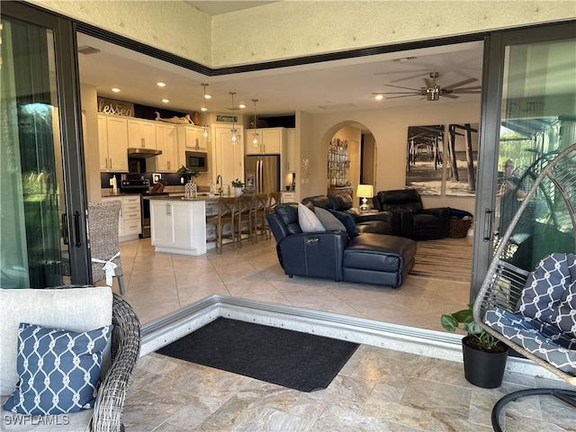 living room featuring arched walkways, a ceiling fan, and recessed lighting