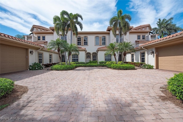 mediterranean / spanish home with decorative driveway, stucco siding, and a tiled roof