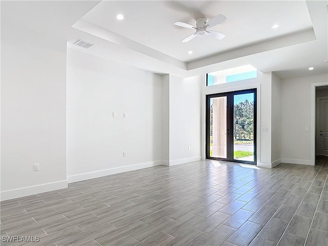 spare room featuring wood tiled floor, a raised ceiling, visible vents, and baseboards