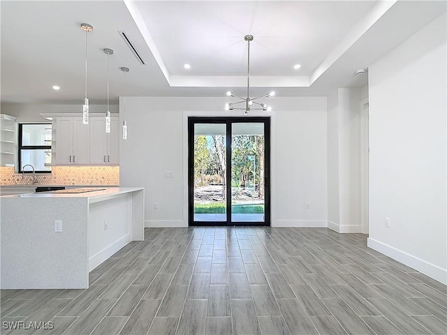 kitchen featuring backsplash, a raised ceiling, light countertops, and open floor plan