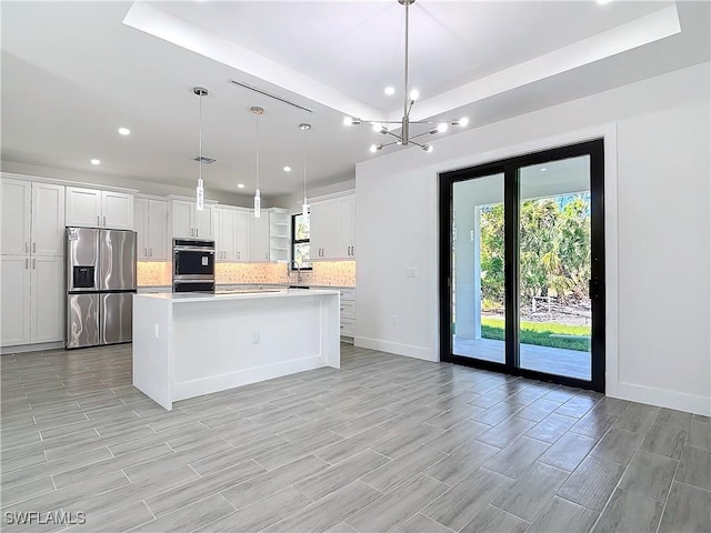 kitchen with stainless steel fridge, white cabinets, a kitchen island, light countertops, and backsplash