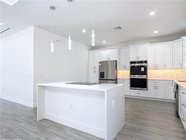 kitchen featuring visible vents, white cabinets, a kitchen island, stainless steel appliances, and backsplash