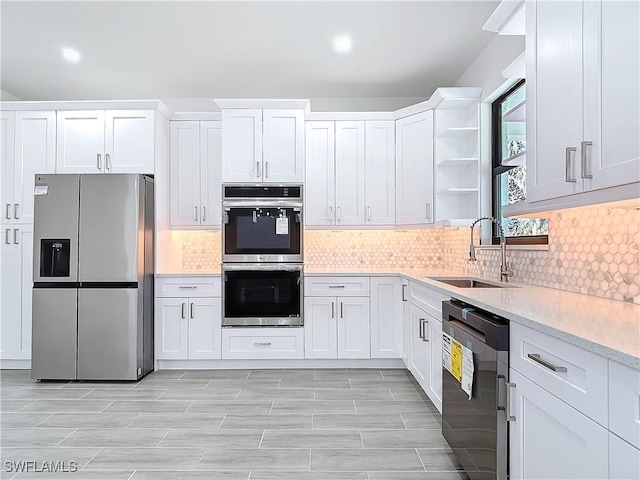 kitchen with a sink, white cabinets, light countertops, appliances with stainless steel finishes, and open shelves