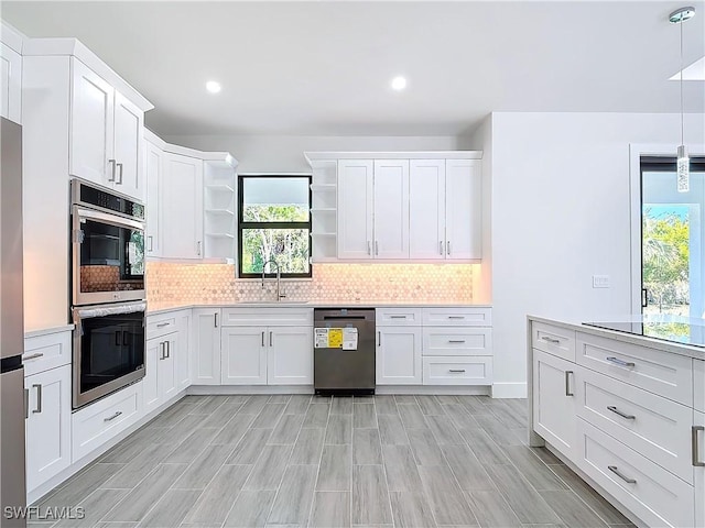 kitchen featuring open shelves, stainless steel appliances, light countertops, decorative backsplash, and a sink