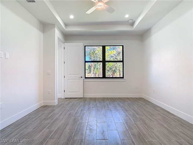 unfurnished room featuring ceiling fan, recessed lighting, baseboards, wood tiled floor, and a raised ceiling