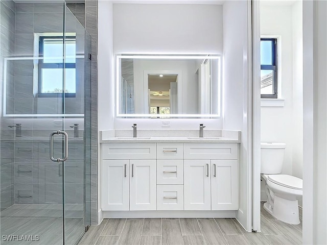 full bathroom with a stall shower, a sink, toilet, and double vanity