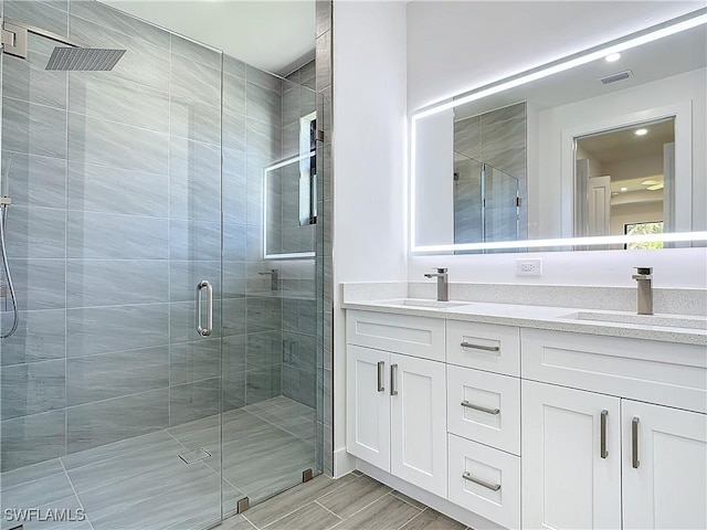 full bath with double vanity, a stall shower, visible vents, and a sink