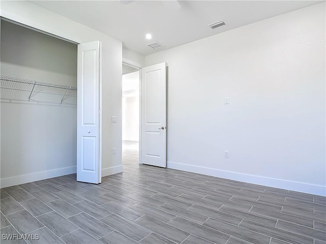 unfurnished bedroom with a closet, visible vents, baseboards, and wood finished floors