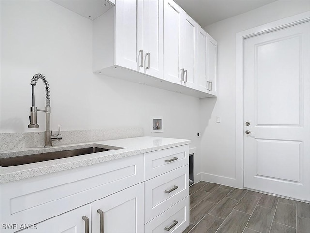 laundry area with cabinet space, baseboards, hookup for a washing machine, wood tiled floor, and a sink