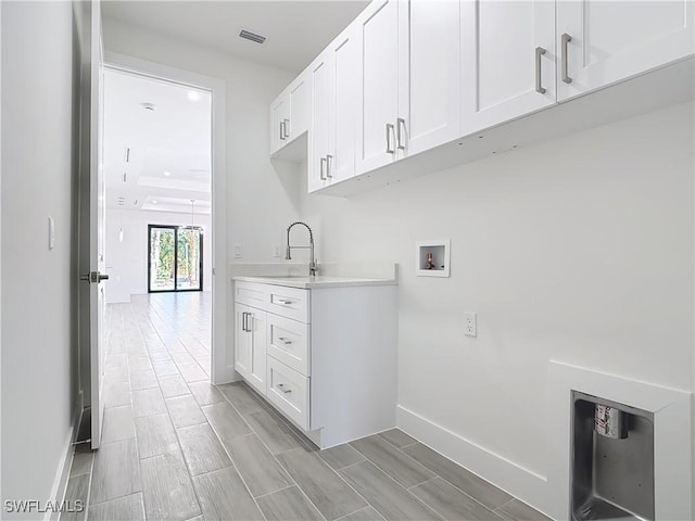 laundry room with washer hookup, a sink, visible vents, baseboards, and cabinet space