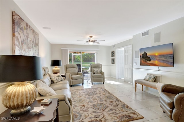 living area with light tile patterned floors, visible vents, a ceiling fan, and baseboards