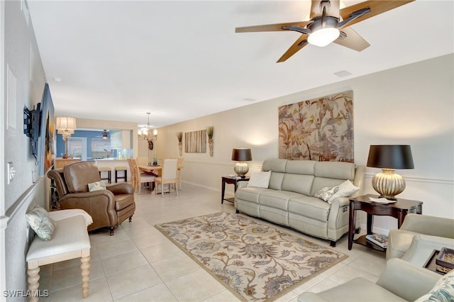 living area with light tile patterned floors and ceiling fan with notable chandelier