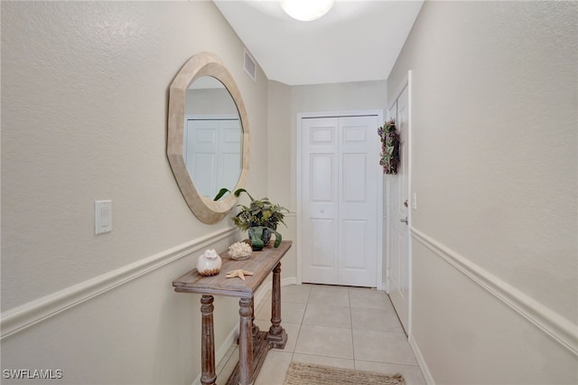 doorway with light tile patterned flooring, visible vents, and baseboards