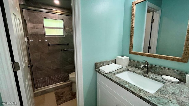 bathroom featuring vanity, a shower stall, and toilet