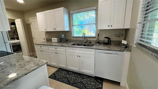 kitchen with white cabinetry, white dishwasher, a sink, and light stone countertops