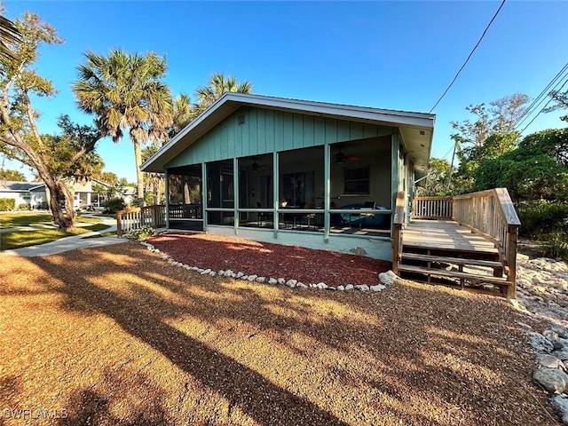 rear view of property with a ceiling fan, a sunroom, and a deck