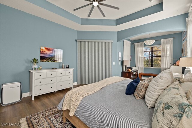 bedroom with baseboards, a tray ceiling, and dark wood finished floors