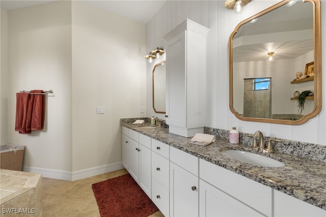 bathroom with double vanity, a sink, tile patterned flooring, and baseboards