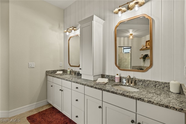 bathroom featuring tile patterned floors, double vanity, a sink, and baseboards
