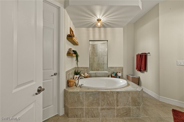 full bath with tile patterned flooring, a bath, and baseboards