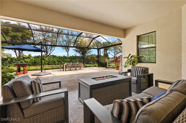 view of patio with glass enclosure, outdoor dining area, and an outdoor living space with a fire pit