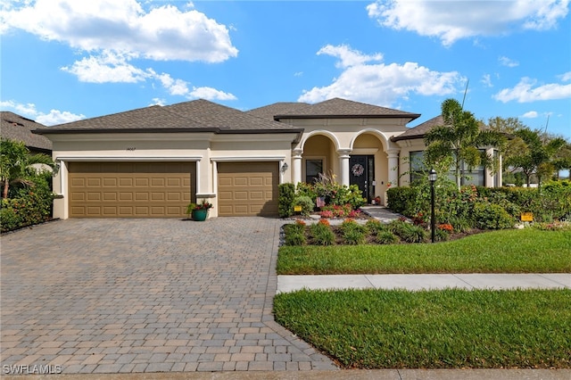mediterranean / spanish-style house featuring a shingled roof, decorative driveway, stucco siding, and an attached garage