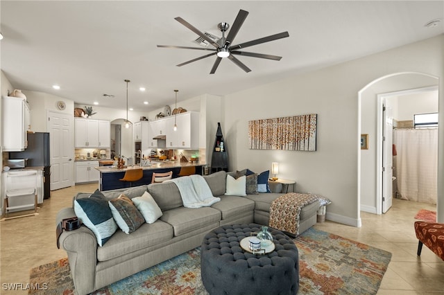 living room with light tile patterned floors, baseboards, arched walkways, ceiling fan, and recessed lighting