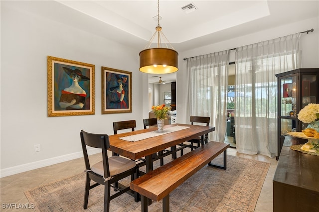 dining room featuring a raised ceiling, light tile patterned floors, baseboards, and visible vents