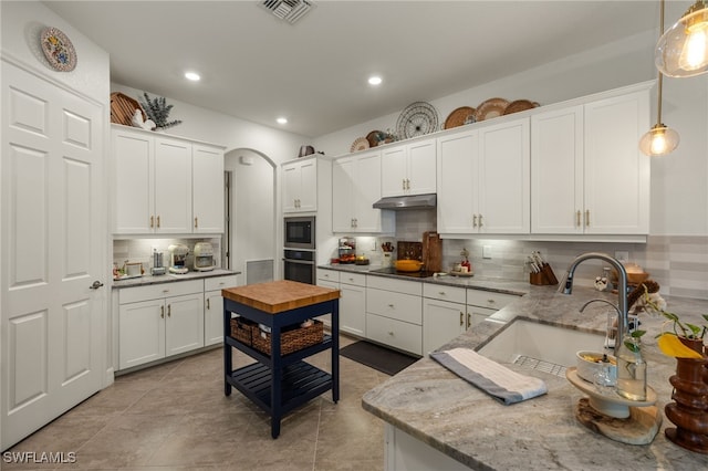 kitchen with visible vents, oven, under cabinet range hood, white cabinetry, and a sink