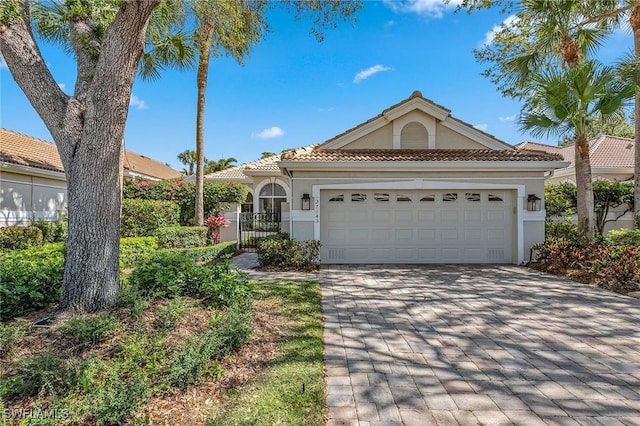 27145 Lost Lake Ln, Bonita Springs, FL 34134 - view of front facade featuring stucco siding, a gate, decorative driveway, a garage, and a tiled roof