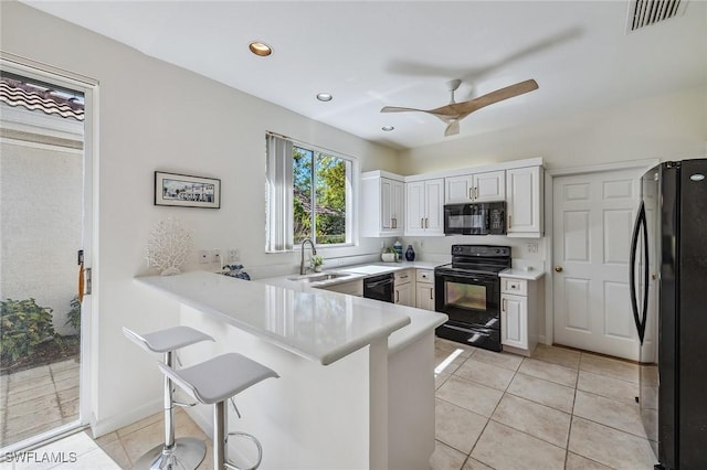 27145 Lost Lake Ln, Bonita Springs, FL 34134 - kitchen with light tile patterned floors, visible vents, a peninsula, a sink, and black appliances