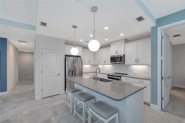 kitchen featuring visible vents, a sink, stainless steel appliances, decorative backsplash, and a breakfast bar area