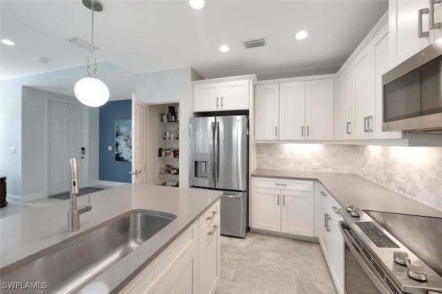 kitchen with white cabinets, decorative light fixtures, visible vents, stainless steel appliances, and a sink