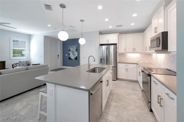 kitchen with tasteful backsplash, visible vents, a sink, open floor plan, and stainless steel appliances