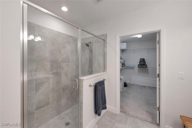 bathroom featuring a shower stall, a spacious closet, and baseboards