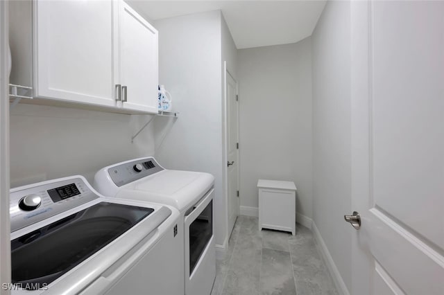 laundry room featuring washing machine and dryer, baseboards, and cabinet space