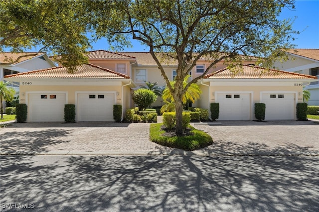 mediterranean / spanish home featuring decorative driveway, a garage, and stucco siding