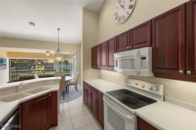 kitchen featuring dark brown cabinets, light countertops, hanging light fixtures, white appliances, and a sink