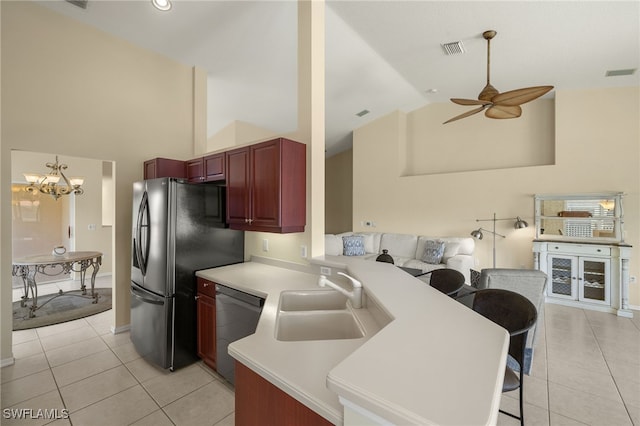 kitchen featuring visible vents, dark brown cabinets, appliances with stainless steel finishes, a peninsula, and a sink