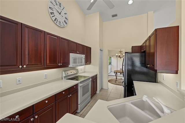 kitchen featuring visible vents, reddish brown cabinets, light tile patterned flooring, white appliances, and a sink